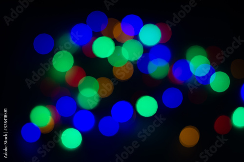Blurry colored circles on a black background. Blurred garland on a black background, christmas background.