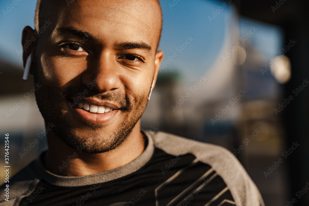 Image of happy african american sportsman in earphones smiling at camera Image of happy african american sportsman in earphones smiling at camera