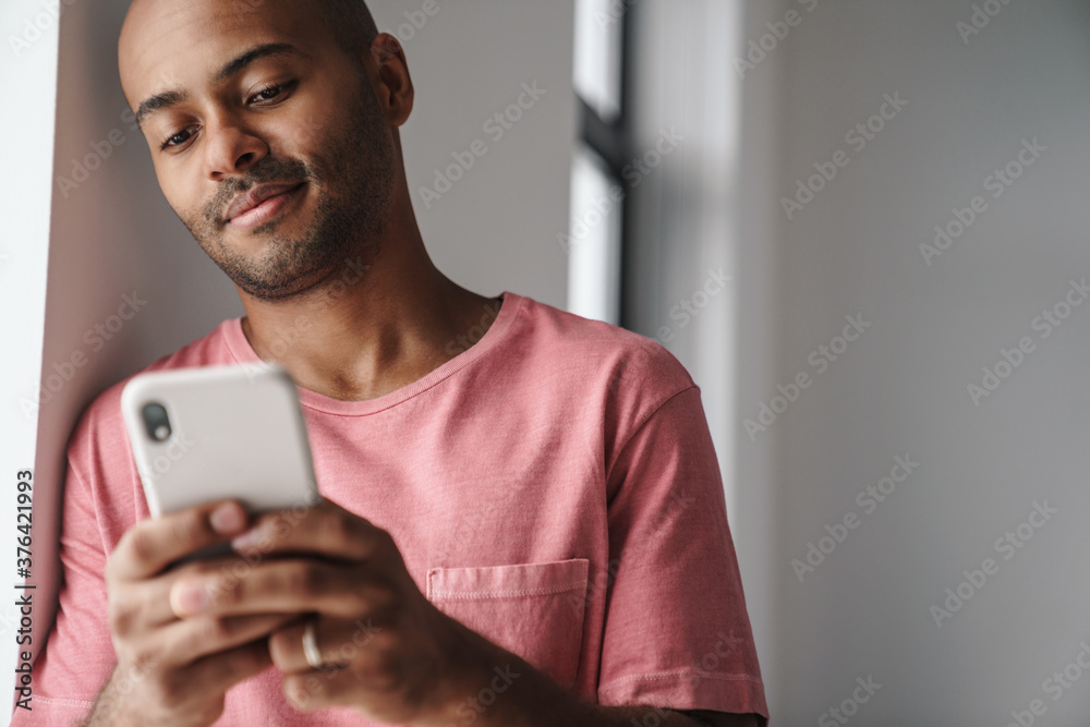 Image of pleased african american guy using mobile phone Image of pleased african american guy using mobile phone