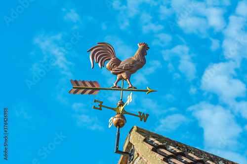 Obraz na plátně Copper cockerel, rooster or chicken weather vane on a farm with blue sky backgro
