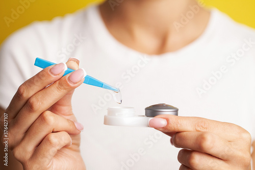 Close up of woman get contact lenses out of container with liquid
