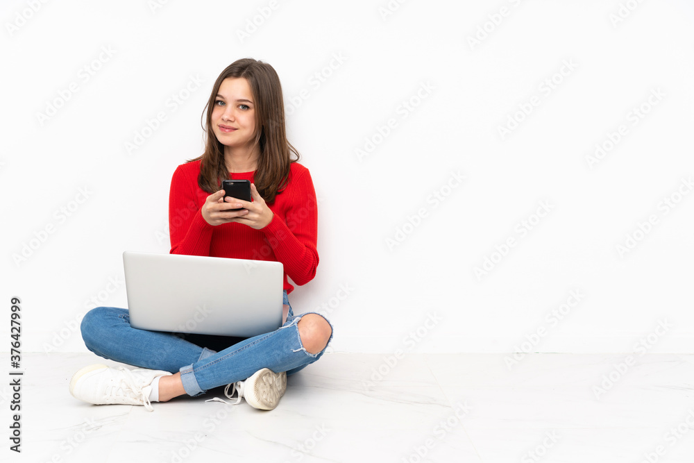 Tenaager girl working with pc isolated on white background sending a message with the mobile Tenaager girl working with pc isolated on white background sending a message with the mobile