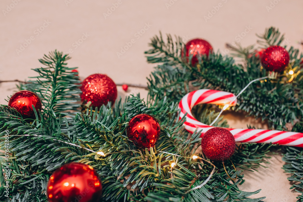 Red Christmas balls, fir branches, a garland with bulbs lie on the table