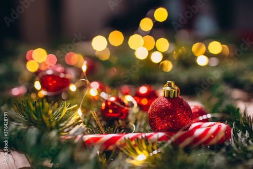 Red Christmas balls, spruce branches, candy in the form of sticks and berries close-up