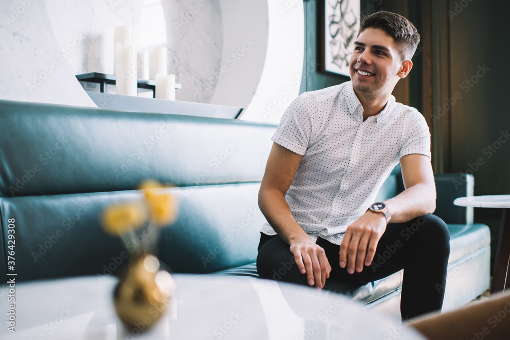 Young man sitting on leather sofa in cozy cafe