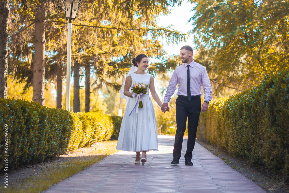 Fototapeta premium happy bride and groom are walking in the green park