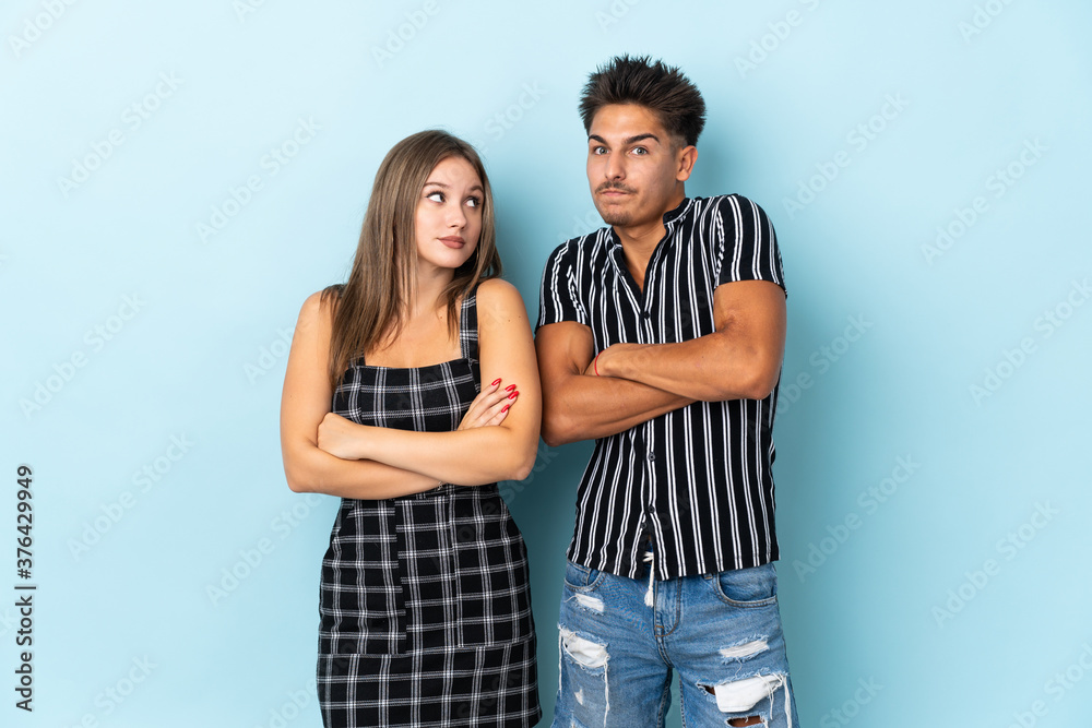Teenager caucasian couple isolated on blue background making doubts gesture while lifting the shoulders Teenager caucasian couple isolated on blue background making doubts gesture while lifting the shoulders
