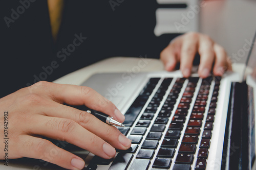 business man with a pen on a notebook computer keyboard