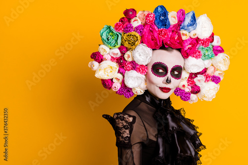 Profile photo of calavera katrina directing thumb look empty space tricking naive young guy wear black dress death carnival costume roses headband isolated yellow color background