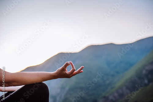 Woman's hand doing yoga with a mountain background
