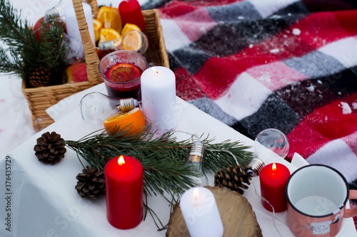 Romantic picnic in winter. There is mulled wine on the table to warm up after a walk. Oranges were added to a cup of mulled wine. There are also candles that are redder and whiter to create coziness. photo