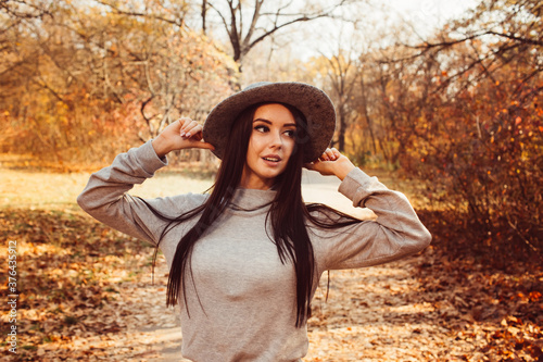 Portrait of a girl in a hat in an autumn park, a woman walks in the woods at sunset