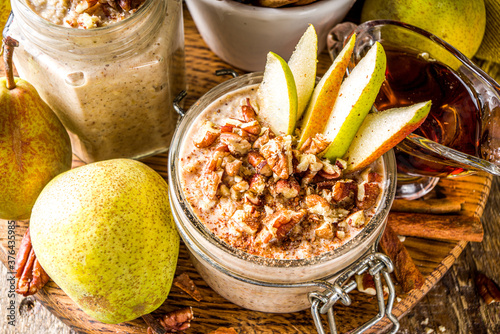 Sweet and spicy autumn breakfast oats recipe, Homemade pear and cinnamon overnight oatmeal with spices and yogurt, wooden background copy space