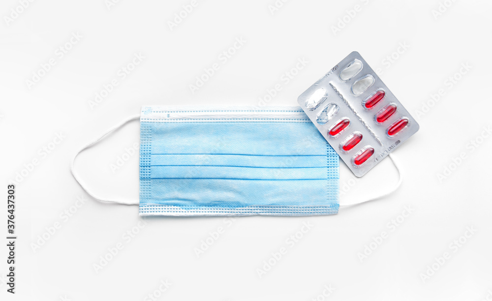 Medical mask and pills. Protection from coronavirus. Covid19 protection concept with pharmaceutical tablets in capsules near a mask. Medical mask and pills. Protection from coronavirus. Covid19 protection concept with pharmaceutical tablets in capsules near a mask.