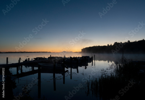 Boats by jetty in on foggy sunrise