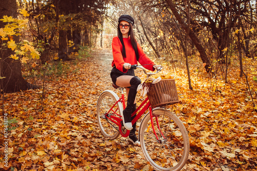 Portrait of a pretty girl with a red bike in the autumn forest