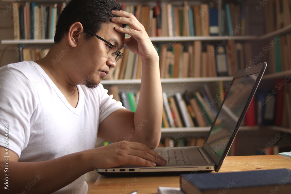 Asian muslim man studying in library, exam preparation concept. Male college student using laptop to learn online Asian muslim man studying in library, exam preparation concept. Male college student using laptop to learn online