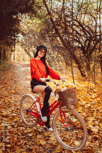 Portrait of a pretty girl with a red bike in the autumn forest