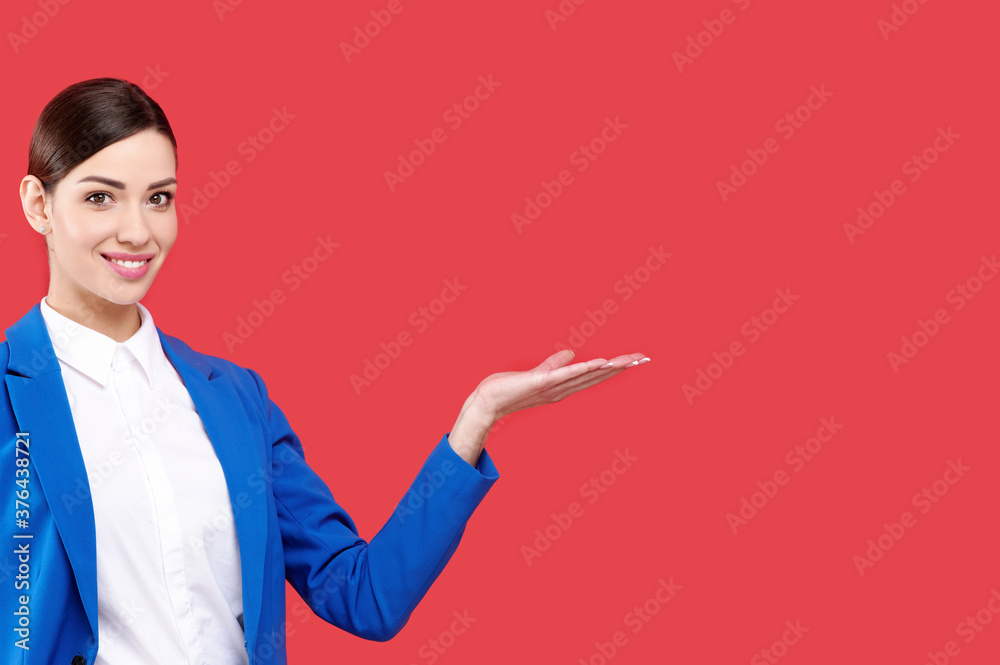 Smiling business woman wearing blue jacket and white shirt holding something on red isolated background, copyspace, business concept Smiling business woman wearing blue jacket and white shirt holding something on red isolated background, copyspace, business concept