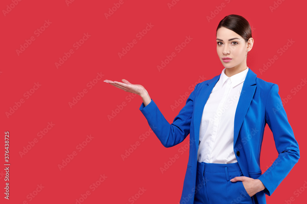 Business woman wearing blue jacket and white shirt holding something on red isolated background Business woman wearing blue jacket and white shirt holding something on red isolated background