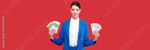 Tableau sur toile Smiling caucasian business woman in blue suit holding euro and dollars banknotes