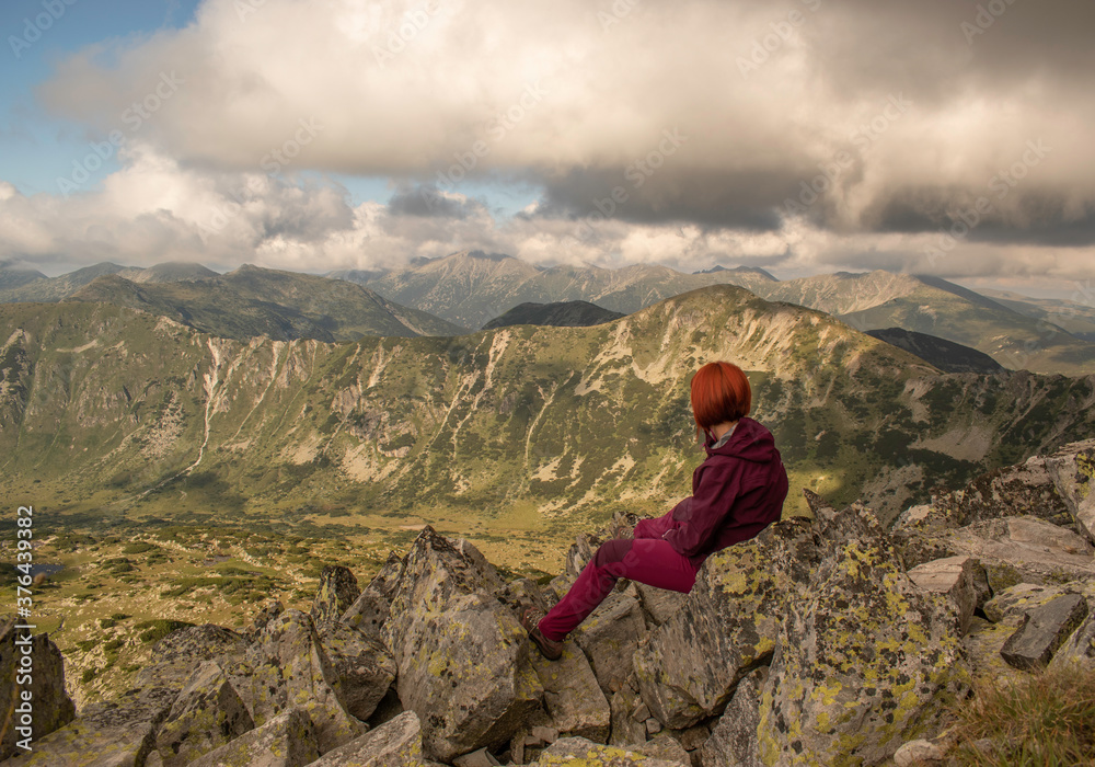 Female hiker enjoys the scenery after fatiguing climbing in Rila mountain, Bulgaria. Yosifitsa peak near sunset. Female hiker enjoys the scenery after fatiguing climbing in Rila mountain, Bulgaria. Yosifitsa peak near sunset.