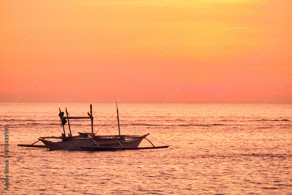 Sunset on Boracay island. Sailing and other traditional boats with tourists on the sea against the background of the setting sun. 