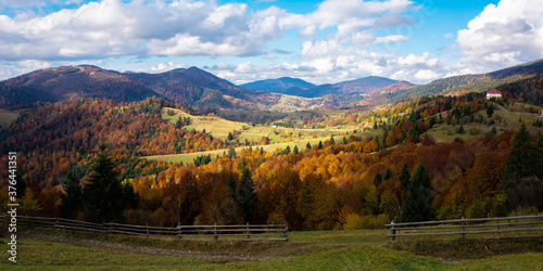 mountainous countryside landscape in autumn. beautiful scenery with forested rolling hills in fall colours. carpathian rural landscape. sunny day with clouds on the sky © Pellinni