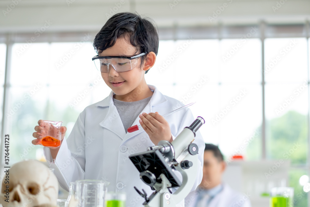 Little boy hold flask contain color chemical and other hand hold dropper during learn to test science experiment with day light. Concept of good practice and education for children support. Little boy hold flask contain color chemical and other hand hold dropper during learn to test science experiment with day light. Concept of good practice and education for children support.