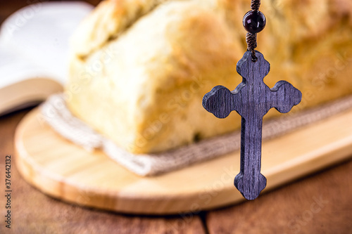 homemade bread made in the Easter and Eucharist period, called Christ bread, religious symbol, with Bible and crucifix in the background