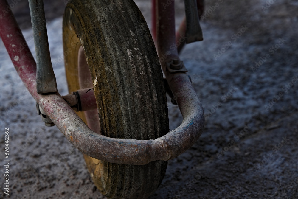 Worn and dirty wheelbarrow wheel at a construction site. Worn and dirty wheelbarrow wheel at a construction site.