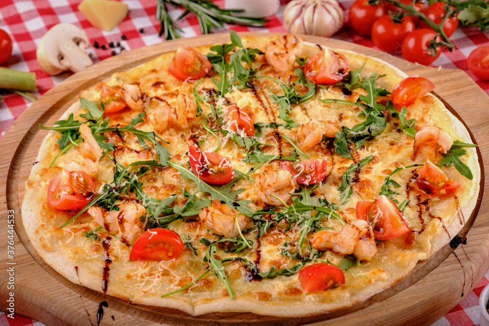 Pizza with seafood, mozzarella, mussels, octopus, squid, salmon, shrimp, cheeseand, fresh rucola and tomatoes sauce, served in italian restaurant background, top view. Mediterranean food.