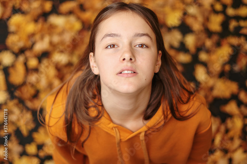 Autumn portrait of teen girl looking up at yellow leaves background. Hello autumn.