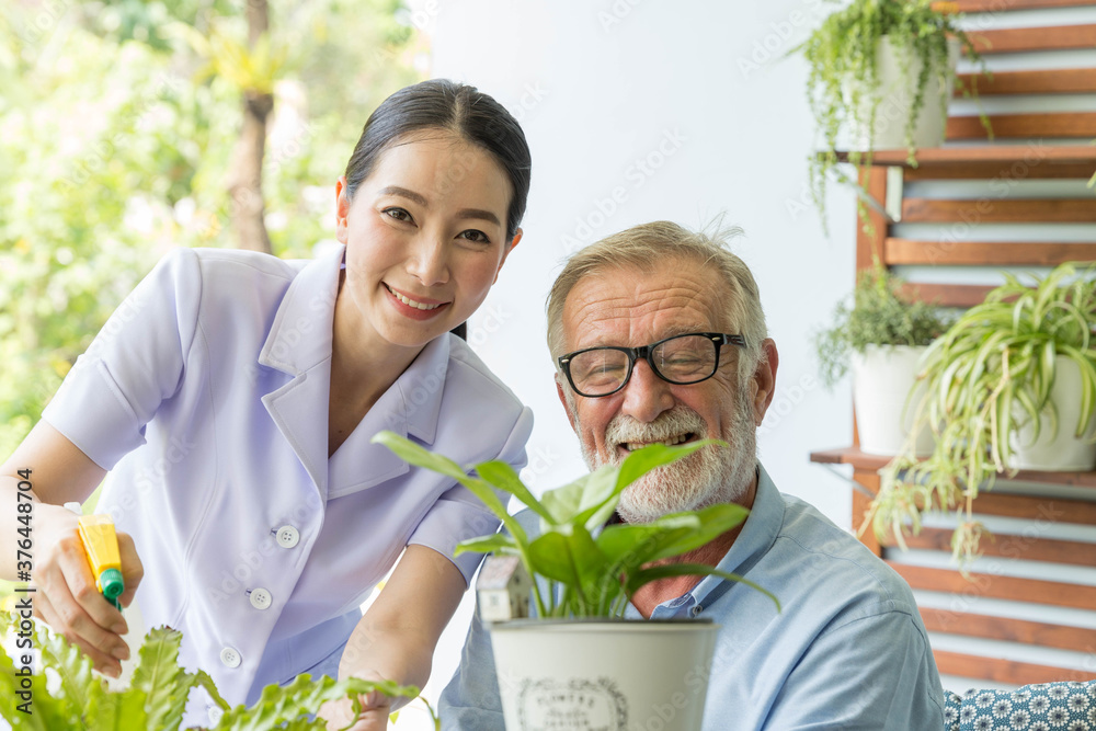 Obraz premium Senior retirement man and nurse are watering a small plant while relax at home