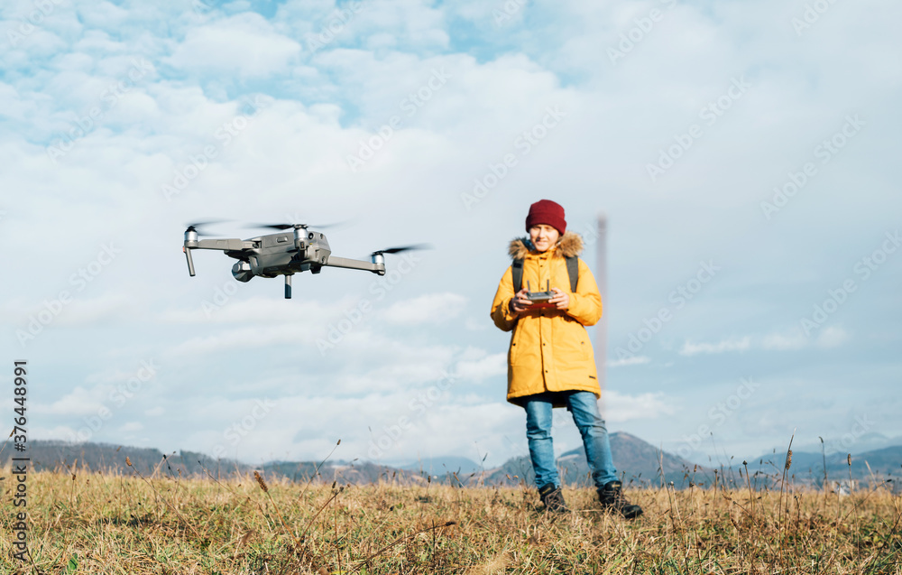 custom made wallpaper toronto digitalClose up image of flying drone with Teenager boy dressed yellow jacket on background piloting a modern digital drone using remote controller