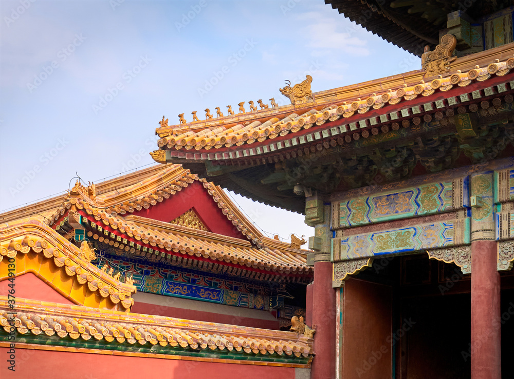 curved roofs with gold patterns in traditional Chinese style with ceramic figures on the blue sky background. The Imperial Palace in Beijing. curved roofs with gold patterns in traditional Chinese style with ceramic figures on the blue sky background. The Imperial Palace in Beijing.