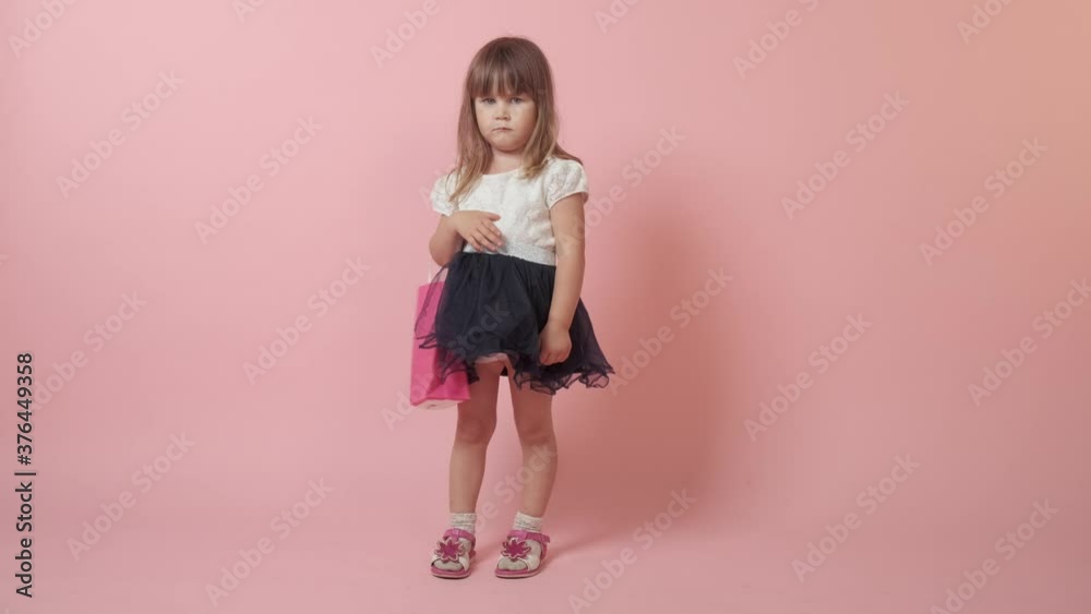 Beautiful cute brunette girl with purchases in her hands. Beautiful bright festive outfit. Pink background. Beautiful cute brunette girl with purchases in her hands. Beautiful bright festive outfit. Pink background.