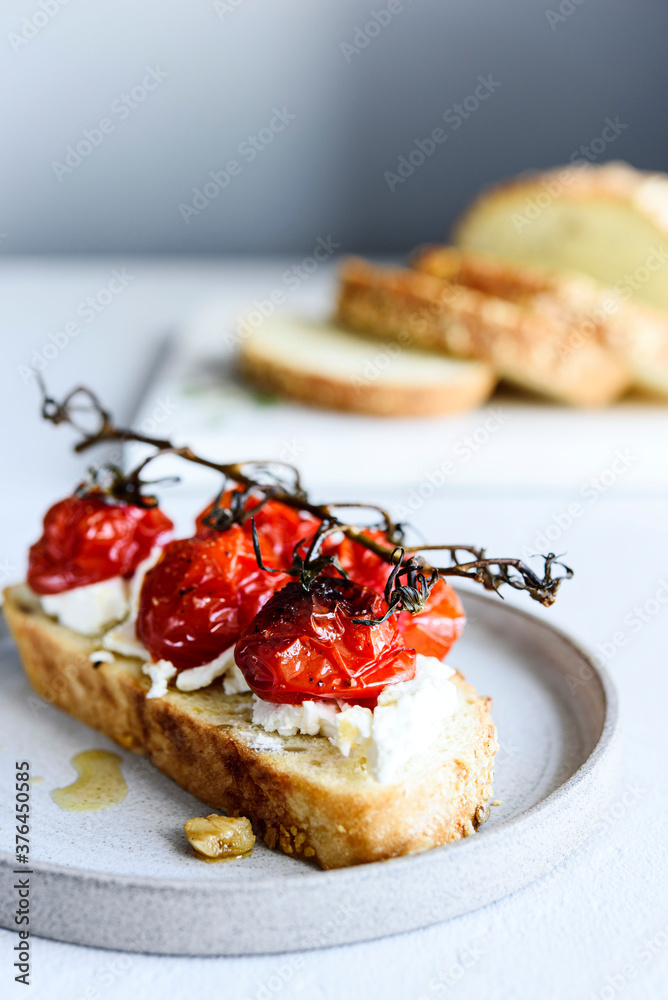 Tomato confit and goat cheese bruschetta on grey concrete table. Selective focus Tomato confit and goat cheese bruschetta on grey concrete table. Selective focus
