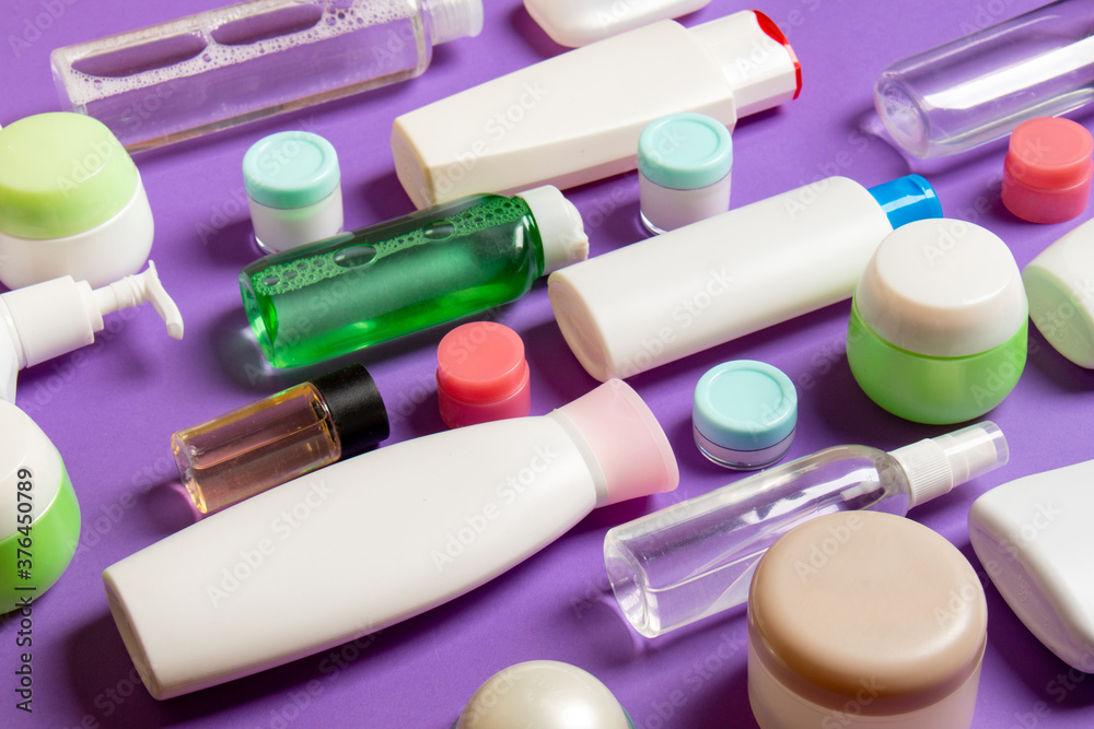 Close-up set of diffrent sized bottles and jars for cosmetic products on colored backgound. Face and body care concept with copy space