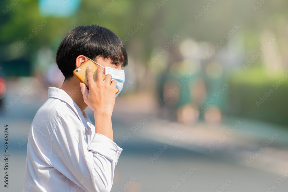 A man is talking on the phone while walking in the city street and wearing Respiratory Protection Mask against covid19, anti-pollution, anti-smog and viruses in city. A man is talking on the phone while walking in the city street and wearing Respiratory Protection Mask against covid19, anti-pollution, anti-smog and viruses in city.