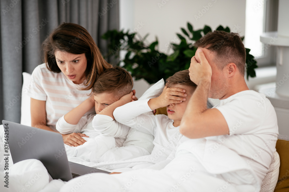 Beautiful parents with kids enjoying at home. Young family watching movie on lap top.. Beautiful parents with kids enjoying at home. Young family watching movie on lap top..