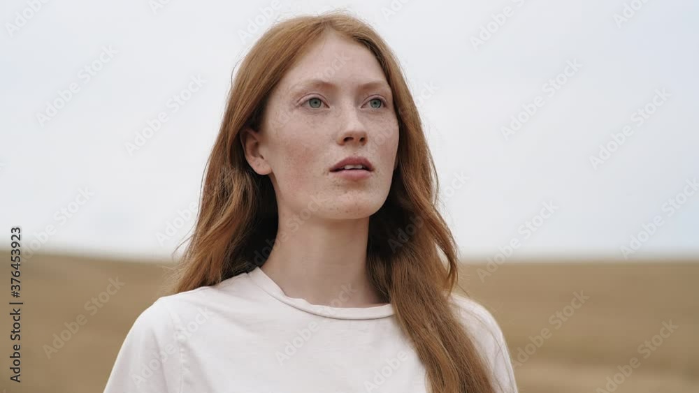 Portrait of happy Ginger young Woman opening her blue Eyes, breathing fresh Air on golden Field. Wind blowing airy Red Hair. Attractive girl with nice Freckles. Natural Beauty. People. Liberty. Portrait of happy Ginger young Woman opening her blue Eyes, breathing fresh Air on golden Field. Wind blowing airy Red Hair. Attractive girl with nice Freckles. Natural Beauty. People. Liberty.