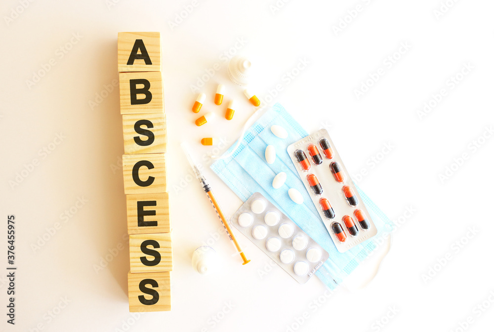 The words ABSCESS is made of wooden cubes on a white background with medical drugs and medical mask. Medical concept. The words ABSCESS is made of wooden cubes on a white background with medical drugs and medical mask. Medical concept.