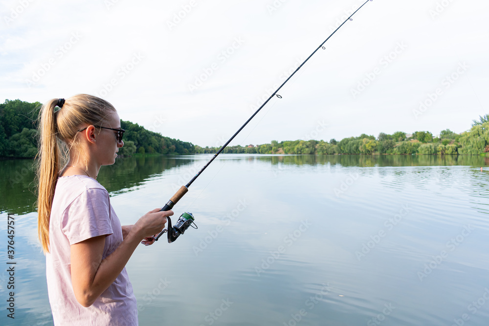 Cute woman is fishing with rod on the summer lake. Woman fishes on the river Cute woman is fishing with rod on the summer lake. Woman fishes on the river
