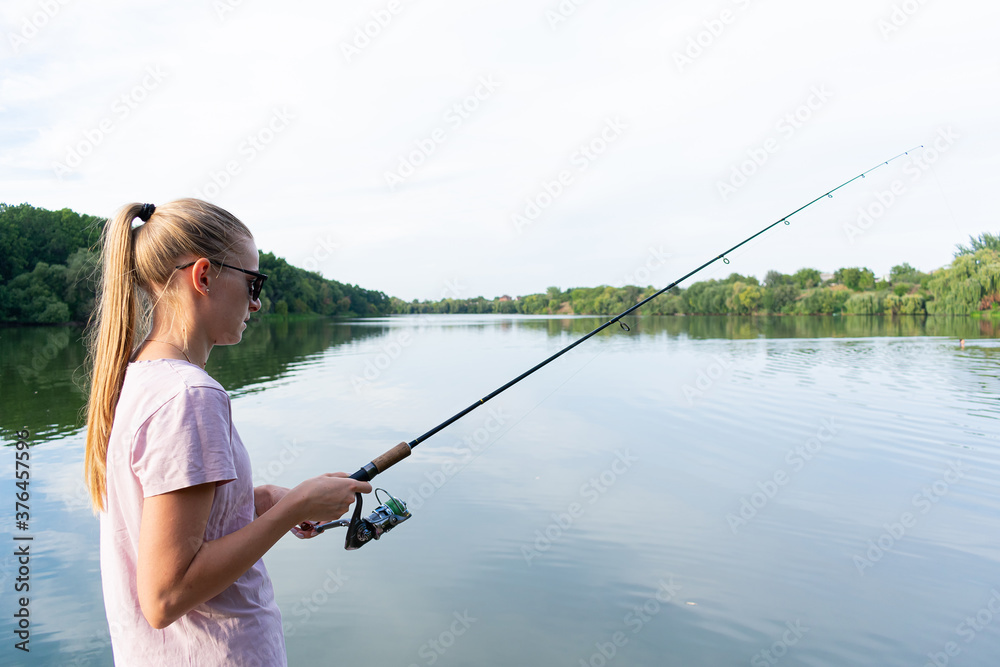 Cute woman is fishing with rod on the summer lake. Woman fishes on the river Cute woman is fishing with rod on the summer lake. Woman fishes on the river