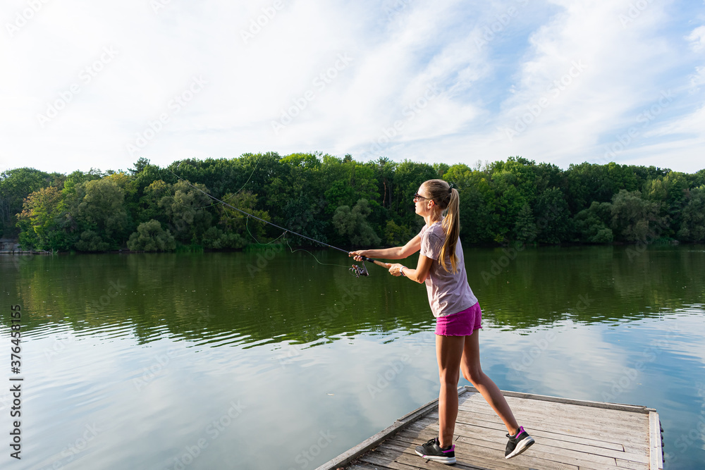 Cute woman is fishing with rod on the summer lake. Woman fishes on the river Cute woman is fishing with rod on the summer lake. Woman fishes on the river