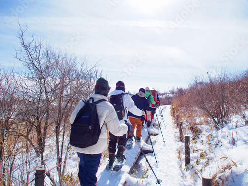 スノーシューで木道の上を歩く人たち