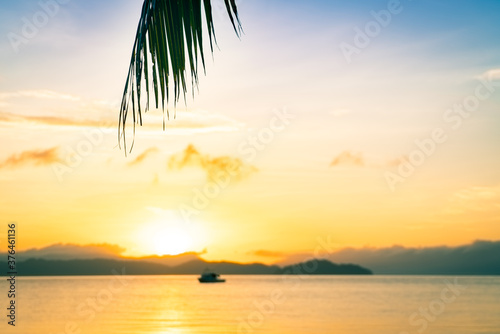 beautiful sunrise on the sea beach with palm tree for travel in holiday relax time - selective focus