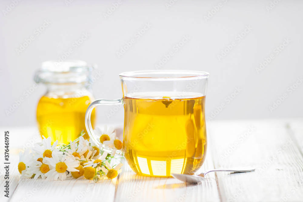 Cup of herbal tea with chamomile flowers and honey on the white wooden background. Natural organic alternative medicine Cup of herbal tea with chamomile flowers and honey on the white wooden background. Natural organic alternative medicine