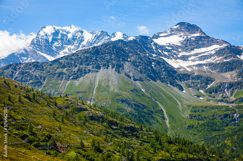 Unique summer Alpine landscape seen from Simplon Pass with rocky mountain ranges and greenery on foothills in Switzerland.